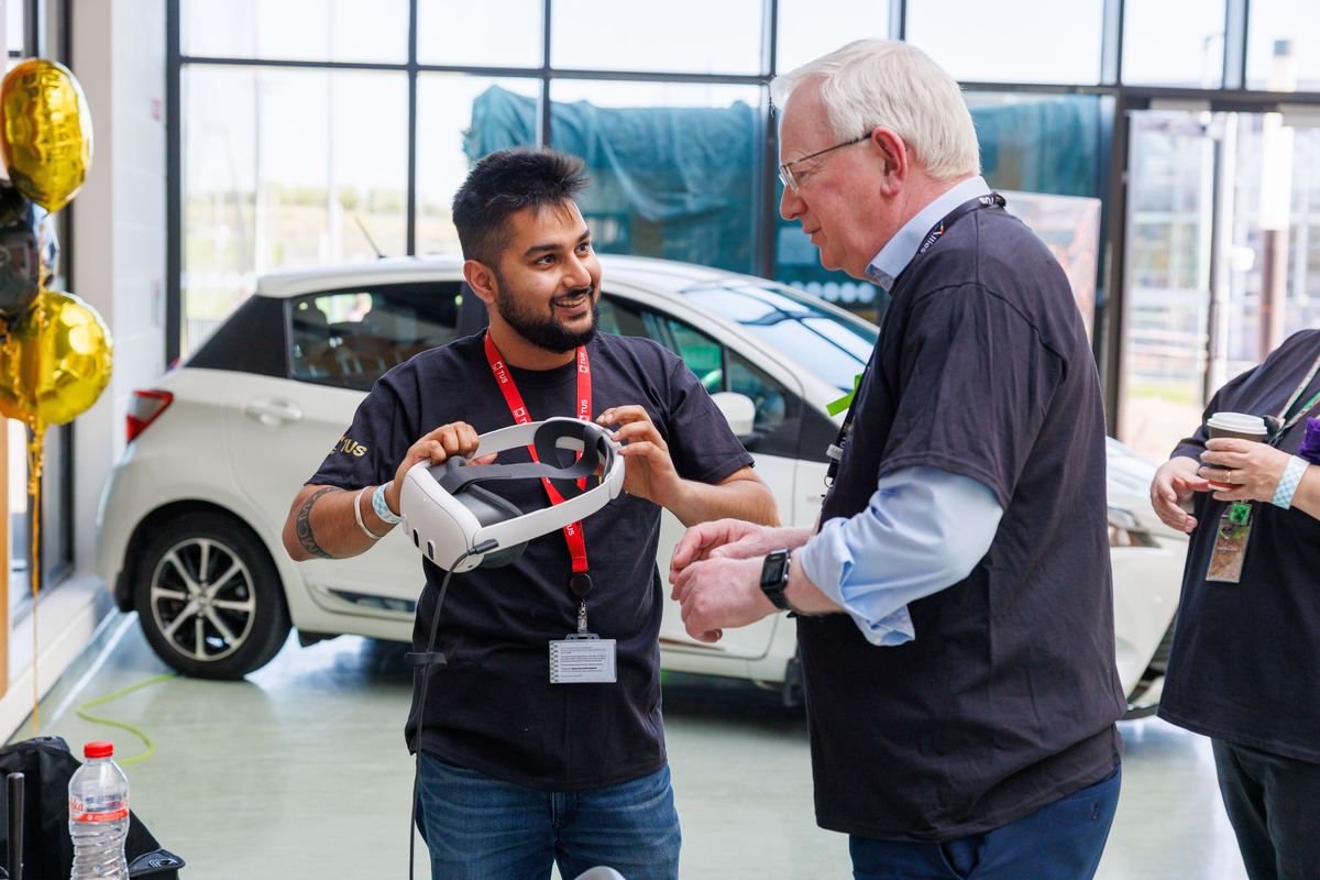 Sahir Sharma handing a mixed reality headset to a visitor at an engineering expo.